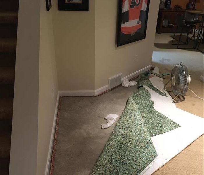 photo of residential basement with carpet pulled back after water damage has occurred 