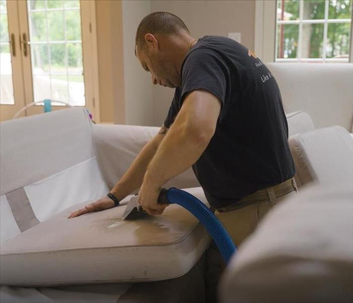 male SERVPRO employee cleaning couch in home