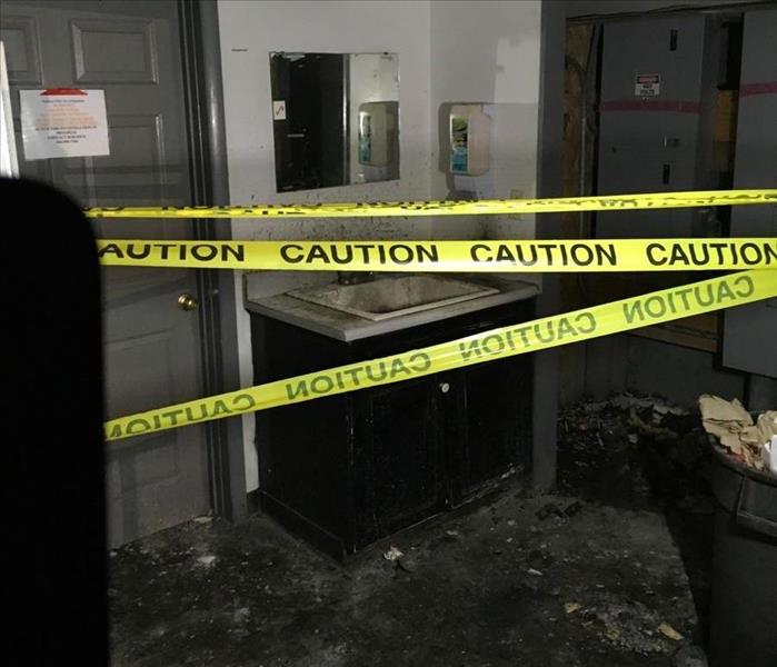 image of commercial bathroom after a fire, taped off with "caution" tape