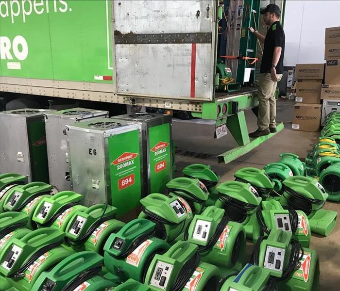 image of several SERVPRO air movers and dehumidifiers places around a SERVPRO semi-truck in a warehouse
