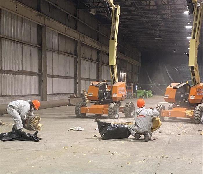 image of SERVPRO workers in PPE/protective gear working in a large commercial warehouse 