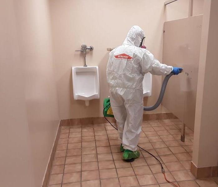 image of SERVPRO worker in full PPE fogging a commercial bathroom 