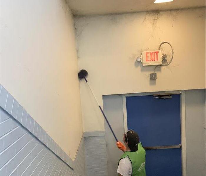 image of SERVPRO worker cleaning soot damage on walls of a commercial building 